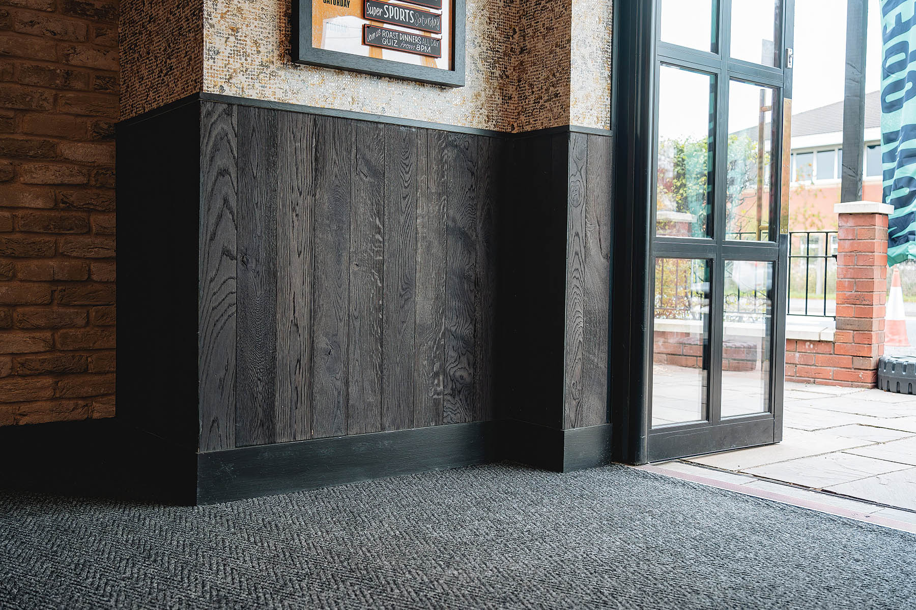Vertical oak wall cladding with charred finish in pub interior