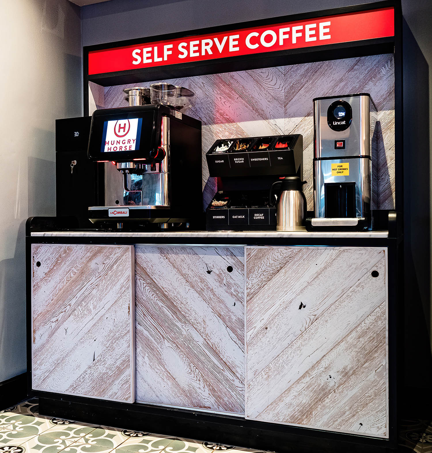 Light oak wall cladding behind self-serve coffee station.