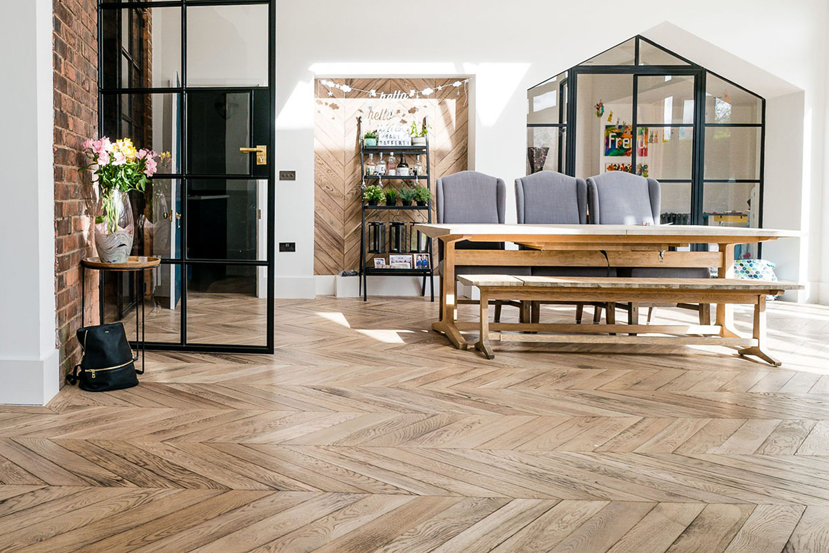 Modern chevron engineered wood floor inside an open-plan residential home.